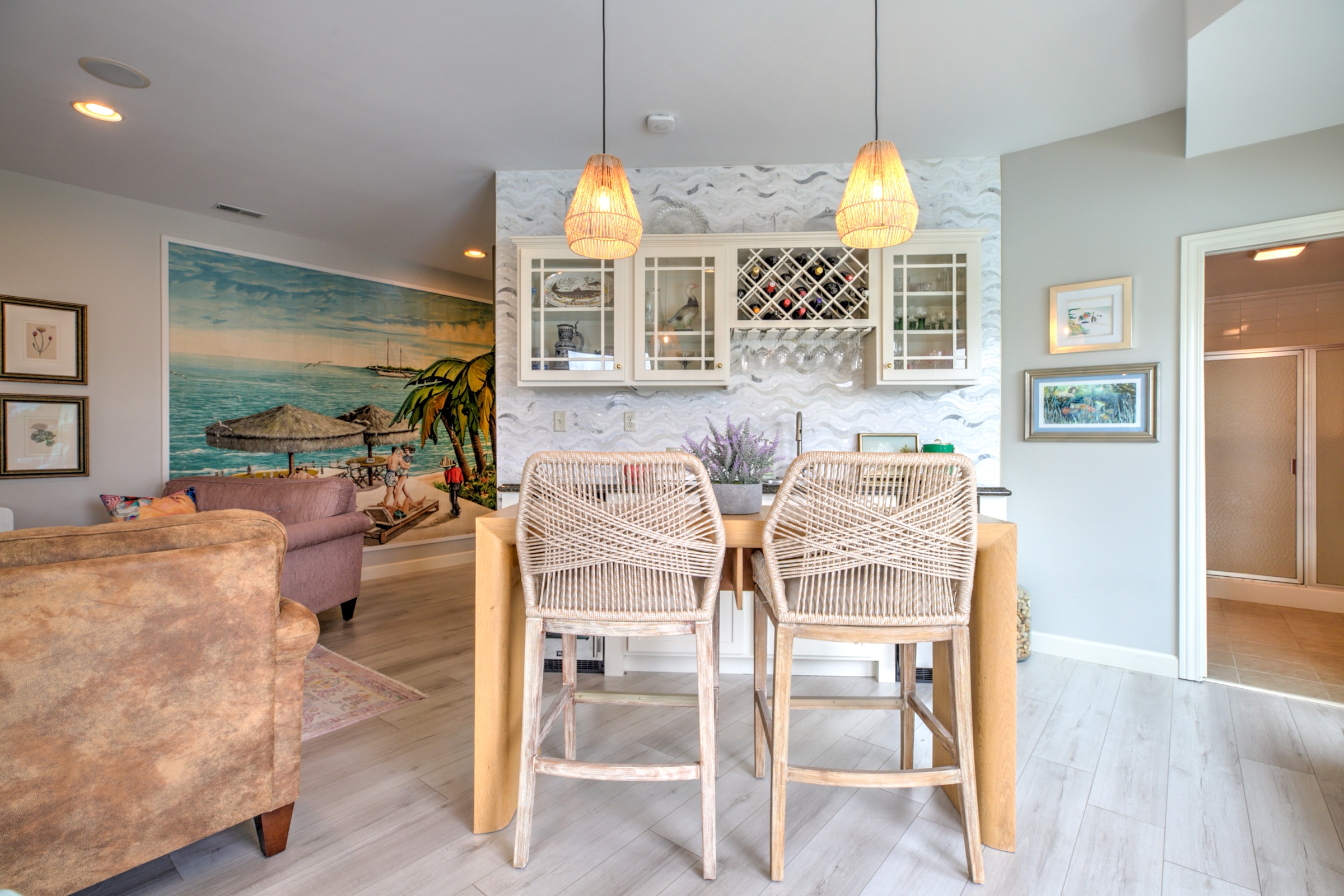 Lower level bar with wine storage, glass front cabinetry, textured tile, and a colorful tropical mural