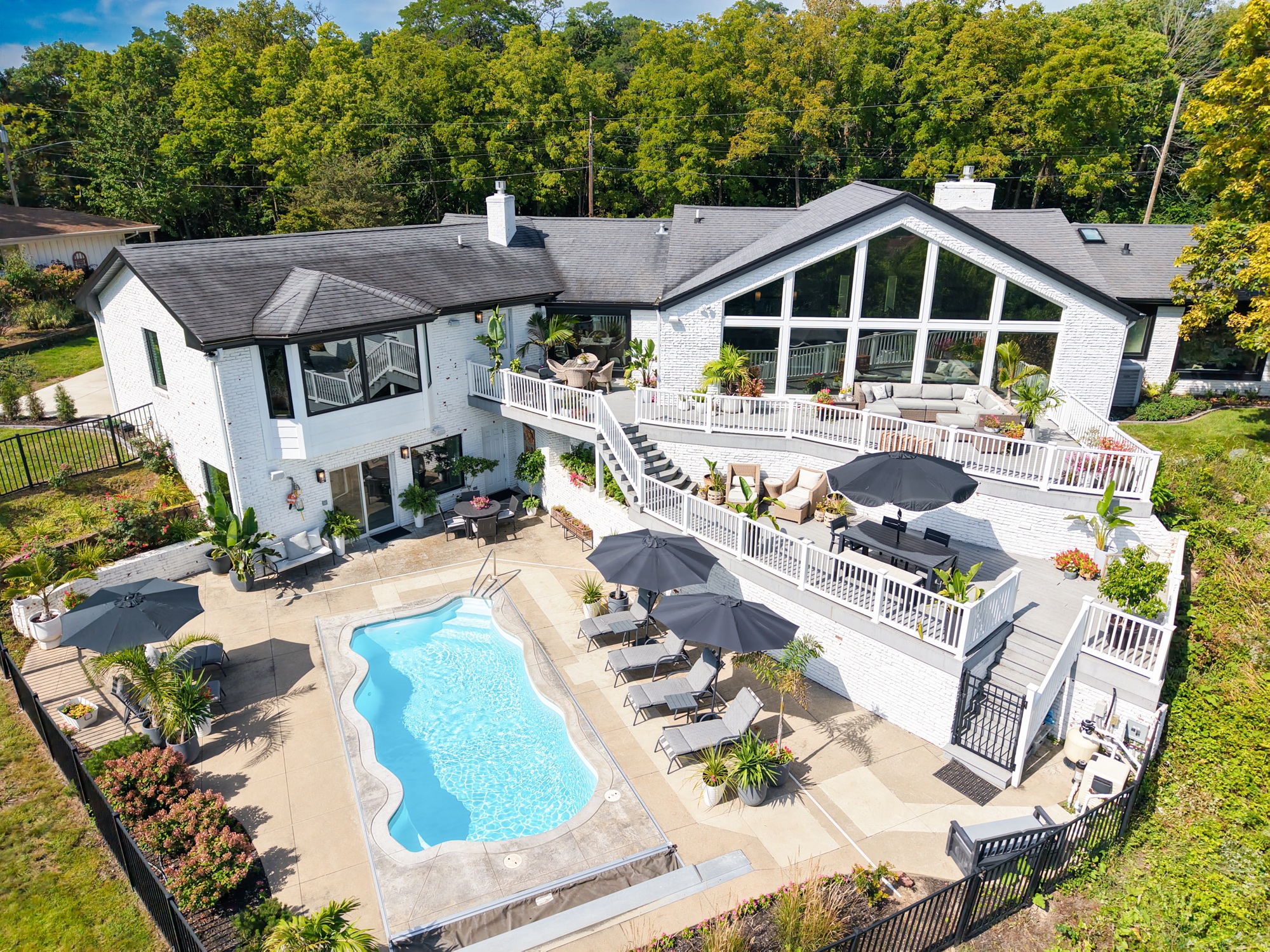 Aerial view showing the pool, multiple terraces, wall of windows, and landscaped backyard